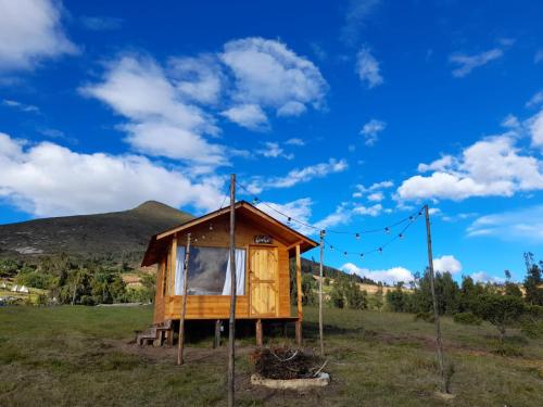uma cabina num campo com uma montanha ao fundo em Camping & Cabaña San Francisco - Guatavita em Guatavita