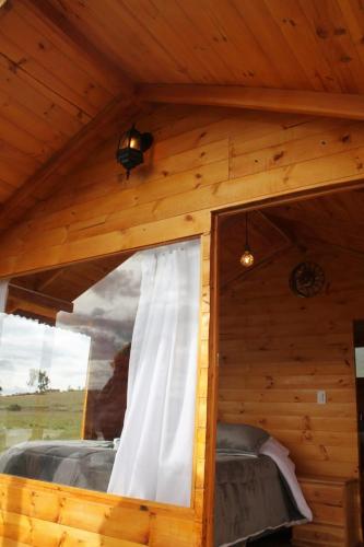 a bedroom in a log cabin with a window at Camping San Francisco - Cabaña, Teepee & Zona de Camping in Guatavita