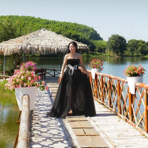a woman in a black dress standing on a bridge at KHU DU LỊCH SINH THÁI HÒN MÁT in Vĩnh Yên