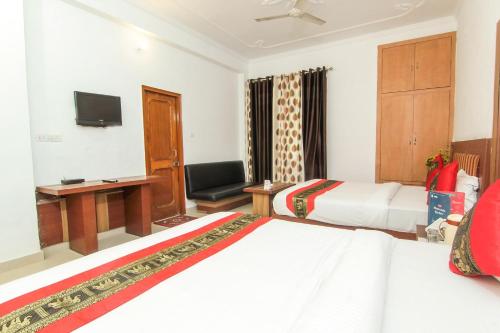 um quarto de hotel com duas camas e uma televisão em OYO Hotel Indiana Near Gomti Riverfront Park em Vibhuti Khand