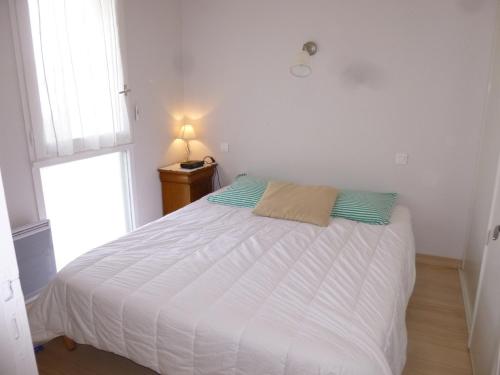 a white bed in a room with a window at Appartement confortable proche plage avec balcon - Saint-Jean-de-Monts, 2 chambres, parking inclus - FR-1-224C-245 in Saint-Jean-de-Monts