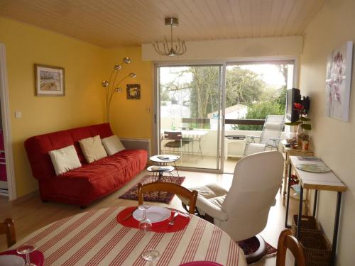 un salon avec un canapé rouge et une table dans l'établissement Appartement confortable proche plage avec balcon - Saint-Jean-de-Monts, 2 chambres, parking inclus - FR-1-224C-245, à Saint-Jean-de-Monts