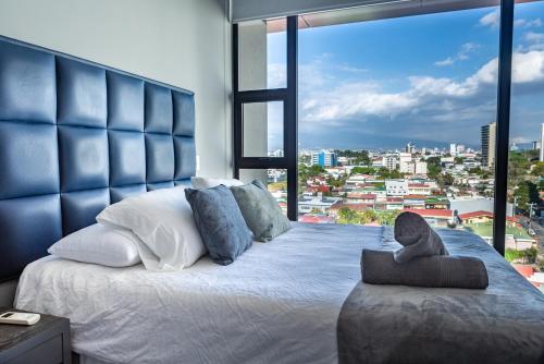 a bedroom with a large bed with a large window at Rooftop Jacuzzi and city view in San José