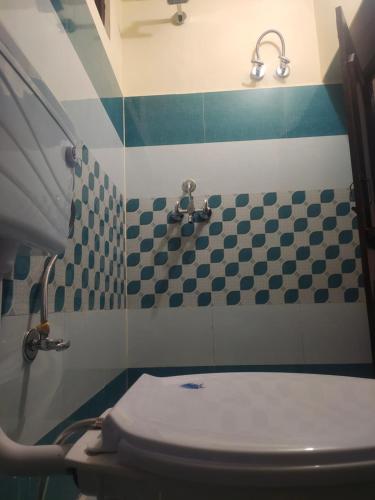 a bathroom with a toilet and blue and white tiles at Krishna Kunj Homestay Rishikesh in Rishīkesh