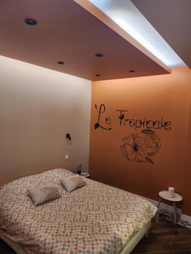 1 dormitorio con 1 cama con un cartel en la pared en La tropicale gite avec Spa 2-4 personnes, 