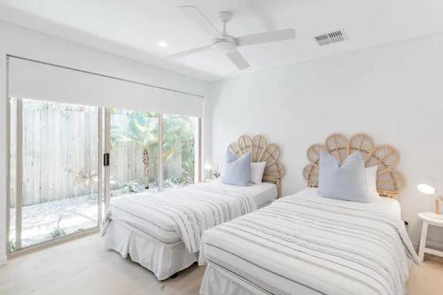 two beds in a white room with a window at Poinciana House—Luxury Noosa Retreat close to Beach in Noosa Heads