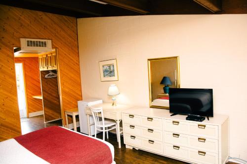 Dormitorio con cama y tocador con TV en Travels Inn Victoria County, en Boularderie East
