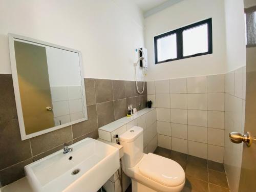 a bathroom with a toilet and a sink and a mirror at Proboscis Guest House Monthly in Sandakan