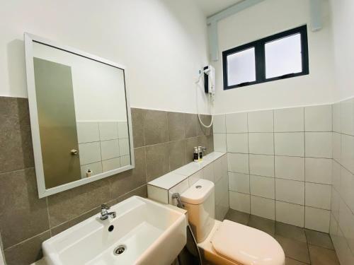 a bathroom with a toilet and a sink and a mirror at Proboscis Guest House in Sandakan