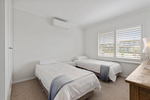 Un dormitorio blanco con dos camas y una ventana. en 13 Kightley Rd - BYO Linen - Pets Negotiable - Wi-Fi, en Goolwa South