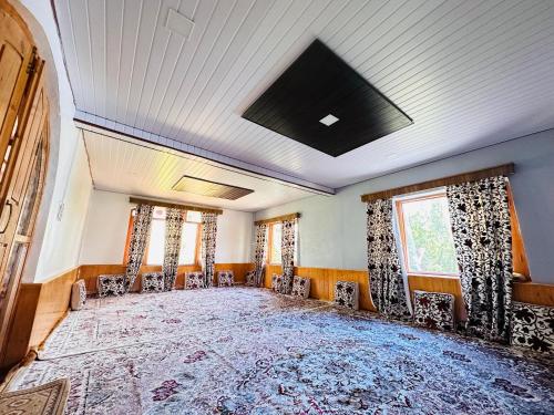 ein leeres Zimmer mit Stühlen und einem großen Teppich in der Unterkunft Sheen Homestay in Gulmarg