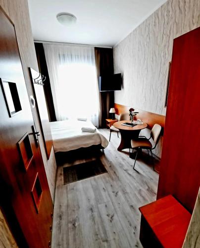 a hotel room with a bed and a table at Hotel Bursztyn in Kalisz