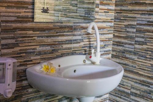 een badkamer met een wastafel met een bloem erop bij The Peace Arta Bungalow in Nusa Penida