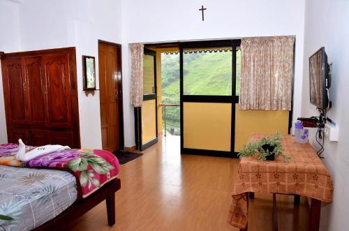 um quarto com uma cama, uma mesa e uma janela em AC MIST em Munnar