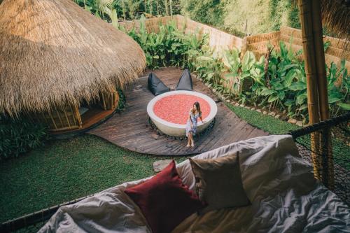 a woman standing next to a bath tub on a wooden deck at Balikayanas - Ellena House in Karangasem