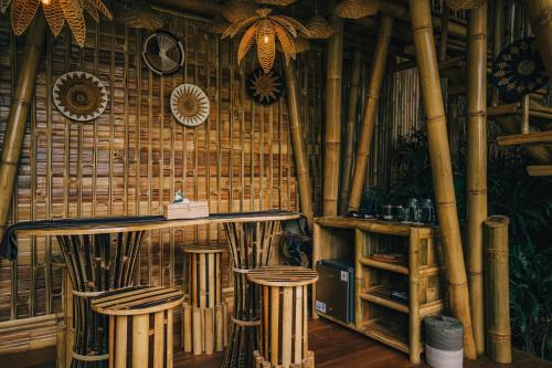 een bar met bamboemuren en krukken in een kamer bij Balikayanas - Ellena House in Karangasem