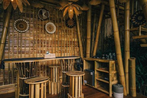 a bar with bamboo walls and stools in a room at Balikayanas - Ellena House in Karangasem