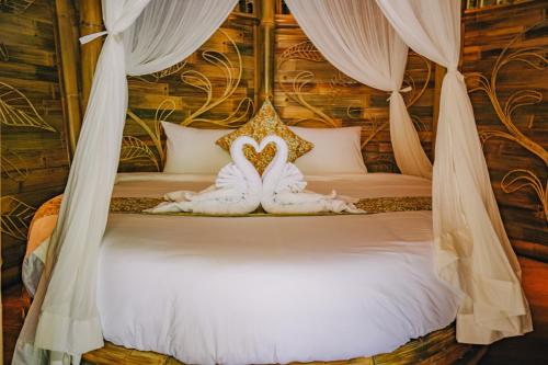 een bed met twee handdoeken in de vorm van een hart bij Balikayanas - Ellena House in Karangasem