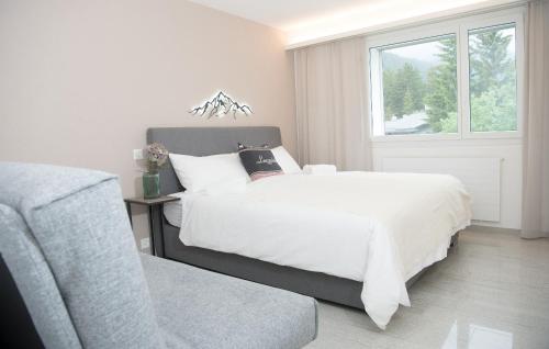 ein Schlafzimmer mit einem weißen Bett und einem Fenster in der Unterkunft Apartment La Riva 105 Lenzerheide with an indoor Pool in Lenzerheide