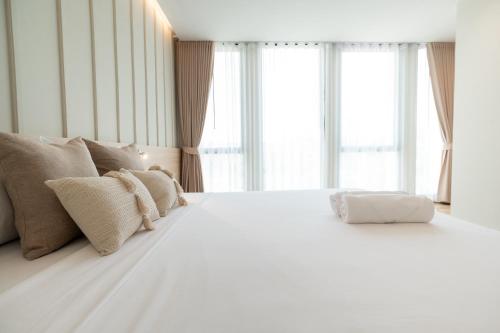 a white bed in a room with windows at Pillows boutique hotel in Chiang Mai