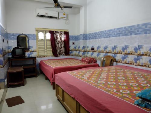 a bedroom with two beds and a tv in it at Jagannath Guest House in Navadwīp