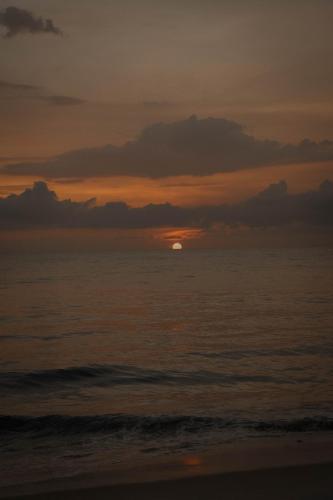 a sunset over the ocean with the sun in the distance at Waves and Shores Beach Villa in Mararikulam