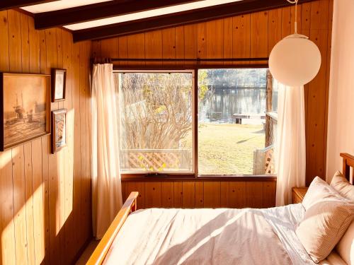 a bedroom with a bed and a window at The Anchorage- A waterfront 70’s retreat in Dora Creek