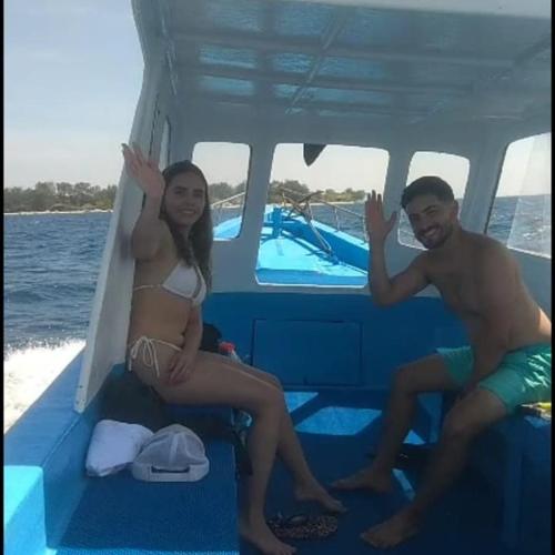 un hombre y una mujer sentados en un barco en Orange's boat trip 3 gili, en Gili Air
