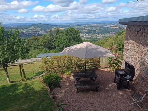 a bench with an umbrella in a garden at Top Barn Wales in Monmouth