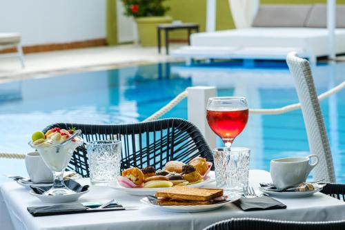 una mesa con comida y una copa de vino junto a una piscina en Fedra Mare, en Agios Stefanos