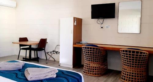 Zimmer mit einem Schreibtisch, einem TV und einem Tisch in der Unterkunft Burdekin Motor Inn in Home Hill