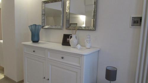 a white cabinet with a mirror and a vase on it at Palazzo Marisa in Fasano