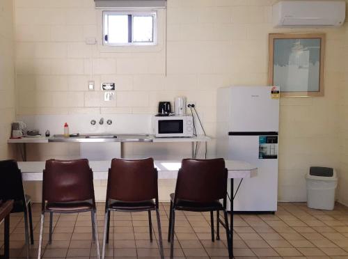 a kitchen with a counter with chairs and a microwave at Burdekin Motor Inn in Home Hill