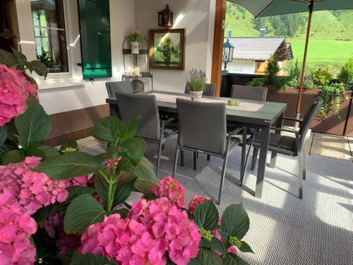 a patio with a table and chairs and pink flowers at Das Bürstegg in Lech am Arlberg