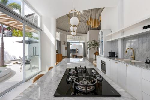 a kitchen with white cabinets and a black counter top at Villa Weiss Berawa in Canggu