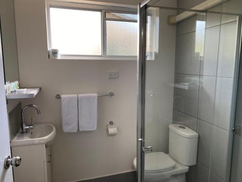 a bathroom with a shower and a toilet and a sink at Tin Can Bay Motel in Tin Can Bay