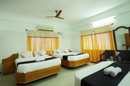 a hotel room with two beds and a fan at Hotel Jeyam in Kanyakumari