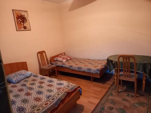 a room with two beds and a table and chairs at гостевой дом "Бумеранг KG" in Cholpon-Ata