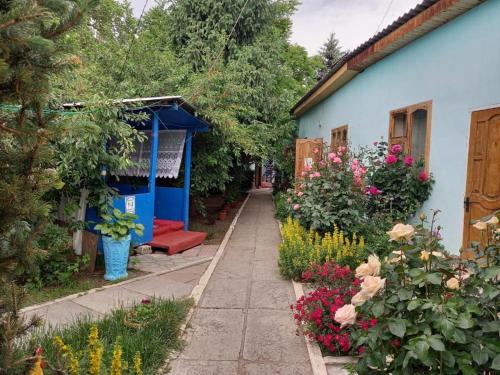 a garden with flowers and a blue house at гостевой дом "Бумеранг KG" in Cholpon-Ata