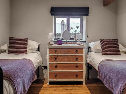 a bedroom with two beds and a dresser with a mirror at The Old Byre in Upper Hulme
