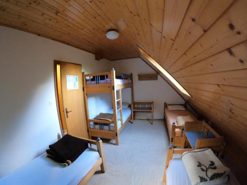 an attic room with two bunk beds and a wooden ceiling at PUS Bavšica in Log pod Mangartom