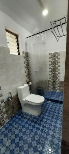 a bathroom with a toilet and a blue tiled floor at Marias house in Siroda