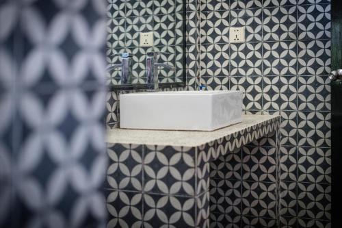 a bathroom with a sink and black and white tiles at The Botanic Garden Hotel in Siem Reap