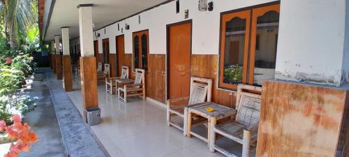 une rangée de chaises et de tables sur un bâtiment dans l'établissement Zian beaugoos homestay, à Ekas