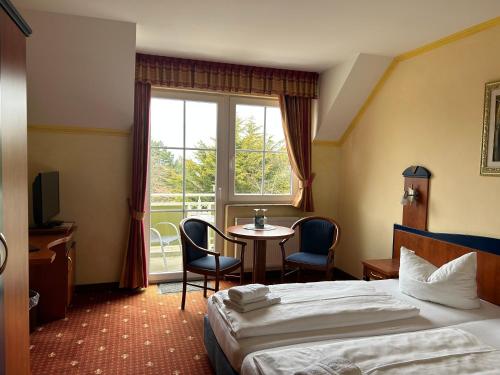 a hotel room with a bed and a table and a window at Hotel Ostseeblick in Karlshagen