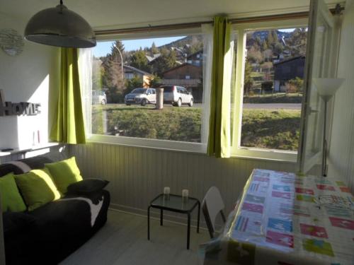 un salon avec un canapé et une grande fenêtre dans l'établissement Joli studio Super Besse, à Besse-et-Saint-Anastaise