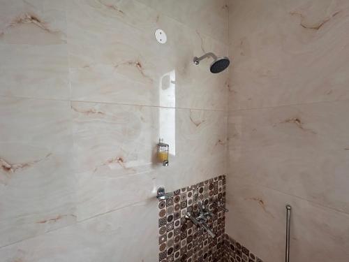 a bathroom with a shower with a tile wall at Green Cottage Oriental in Panchkula