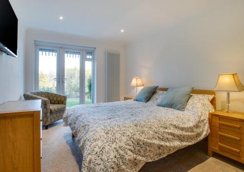 a bedroom with a bed and a chair and a window at Sandpipers in Rottingdean