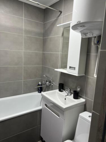 a bathroom with a sink and a toilet and a bath tub at Однокомнатная квартира in Balqash
