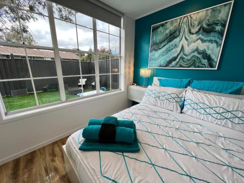 a bedroom with a bed with blue walls and windows at Tiny House in Belconnen 1BR Self Contained Wine in Higgins